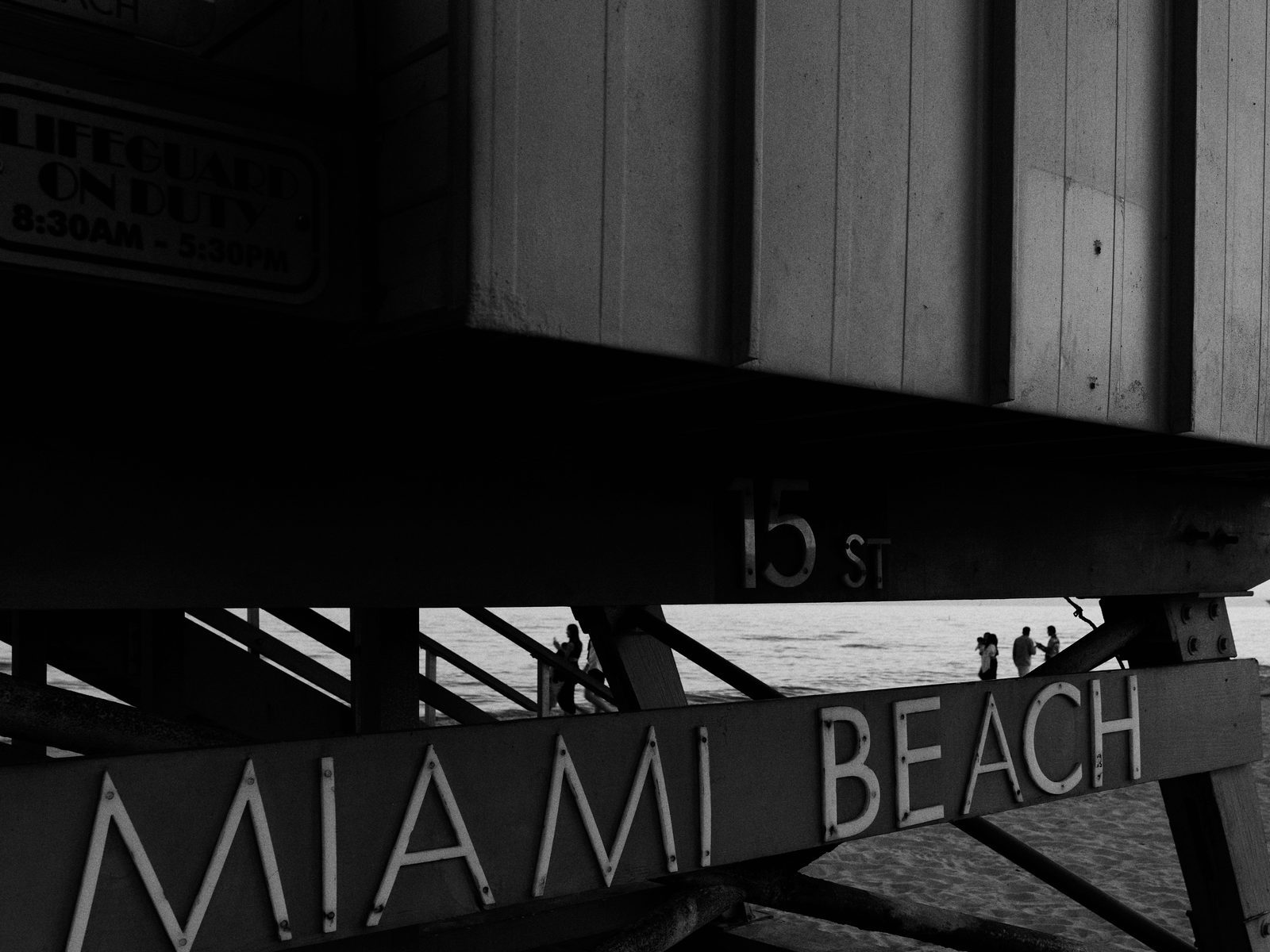 A lifeguard stand on the beach in Miami at dusk, people at the water's edge beyond
