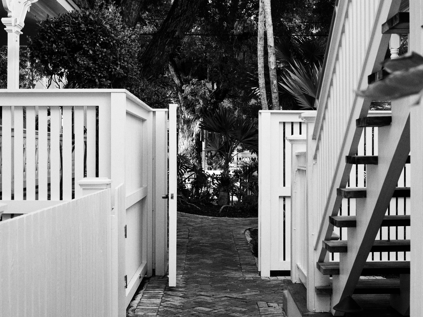 A garden gate standing open onto a private courtyard path