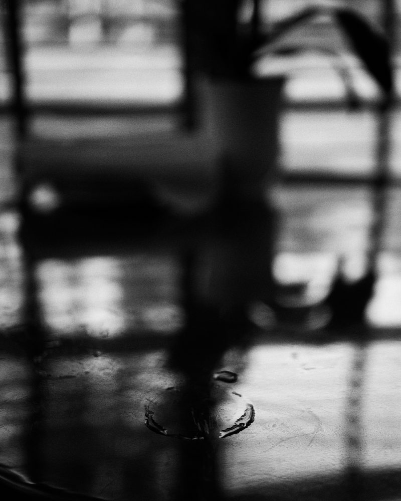 A water ring left on a cafe table, window light falling across it
